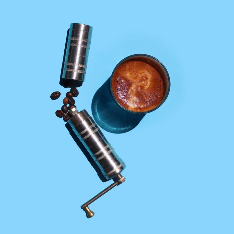 Coffee grinder and cup on sky blue