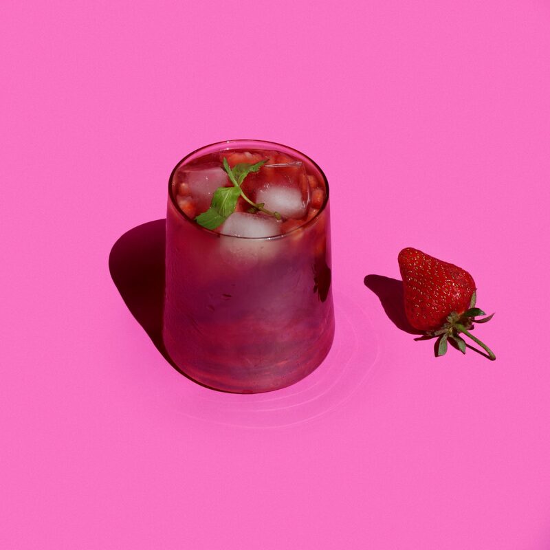 Red iced drink with strawberry on pink